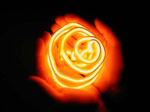 A red neon coil casts a soft red glow upon the hands